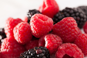 handful of raspberry and blackberry berries on white background