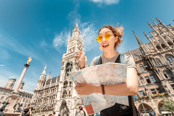 Happy asian woman with map searching for sights and interesting places in Munich city with Town...