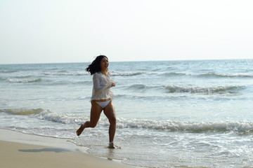 Fototapeta na wymiar Beautiful young woman in white sportswear running on beach