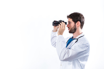 Medico con binocolo e stetoscopio sta cercando la terapia giusta. Sfondo bianco