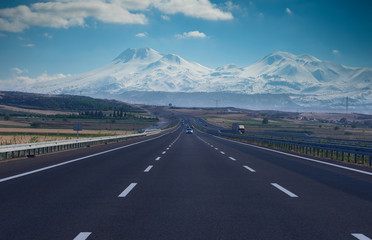 Straight leading highway and snowy mountains in background