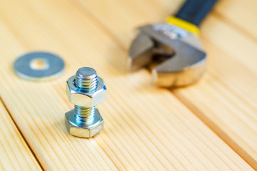 Metal bolts and nuts on wooden background with adjustable wrench