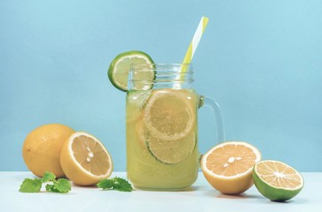 Lemonade drink of soda water, citrus and mint on the light blue background. Cocktail glass with...