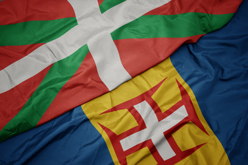 waving colorful flag of madeira and national flag of basque country.