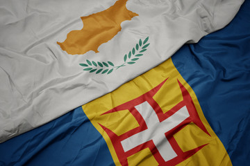 waving colorful flag of madeira and national flag of cyprus.