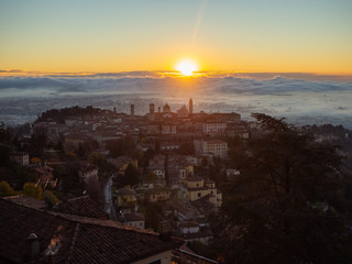 Bergamo, one of the most beautiful city in Italy. Amazing landscape of the old town and the fog covers the plain at sunrise. Fall season