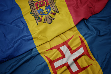 waving colorful flag of madeira and national flag of moldova.