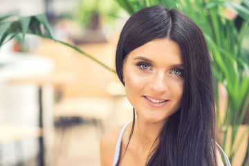 Beautiful smiling young brunette woman with long black hair against of summer background. Portrait of beautiful smiling woman with long hair outdoors.