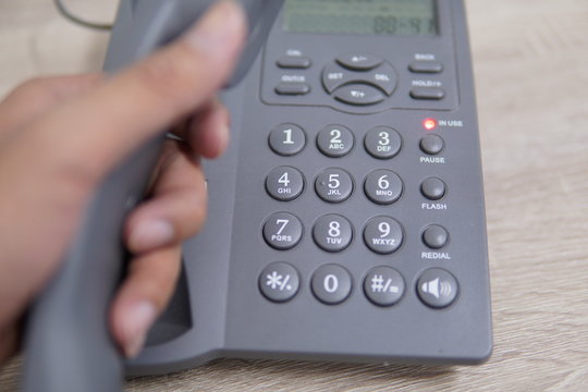 Male Hand Holding Telephone And Dailing A Phone Number.	