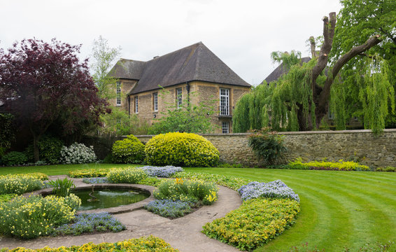 Beautiful english garden in Oxford (United Kingdom, England). Nice old stone house in the background. Peaceful place. Mesmerizing green nature around it. Relaxing place in the UK.