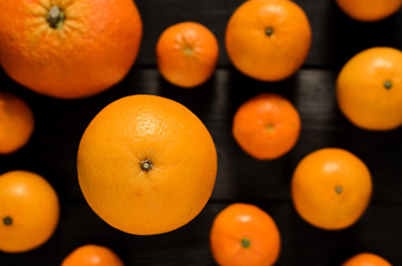 Raw several mandarins and orange isolated on black wooden background