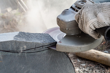 Man's hands holding angle grinder and cutting  a stone