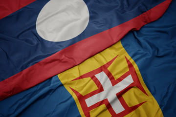 waving colorful flag of madeira and national flag of laos.