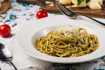 Delicious italian pasta spaghetti with pesto sauce, cherry tomato and cheese. Close up. Italian style