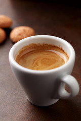 Cup of coffee with amaretti (Italian biscuits) on rustic wooden background. Close up.