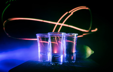 Club drink concept. Tasty alcohol drink cocktail tequila with lime and salt on vibrant dark background or glasses with tequila at a bar