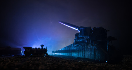 German canon on the train. World wars weapon resized artwork on table with dark toned foggy background. Battle scene.