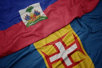 waving colorful flag of madeira and national flag of haiti.