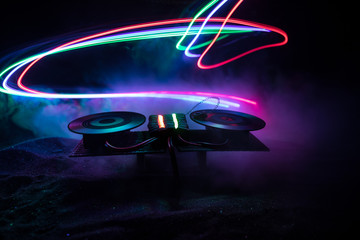 Dj club concept. Creative artwork decoration of dj table on dark toned background with lights and fog. - obrazy, fototapety, plakaty
