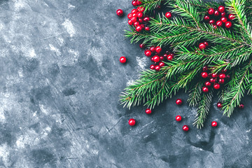 Christmas and New Year background with winter berries and fir branches in a dark style. Copy space and top view.