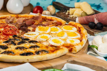 Italian Four Seasons Pizza. Close up. On the blue table.