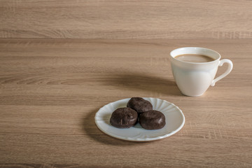 a cup of morning coffee latte with chocolate candies on a plate