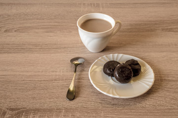 a cup of morning coffee latte with chocolate candies on a plate