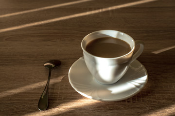 cup of morning latte coffee with saucer and spoon on the table