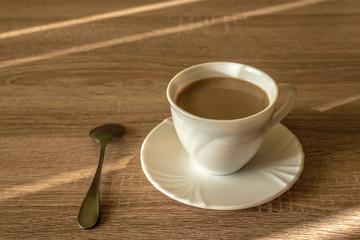 cup of morning latte coffee with saucer and spoon on the table