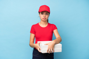 Young woman holding a pizza over isolated pink wall pleading