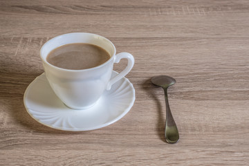 cup of morning latte coffee with saucer and spoon on the table