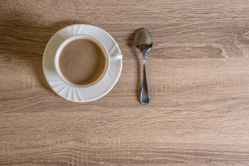 cup of morning latte coffee with saucer and spoon on the table