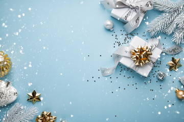 Merry Christmas and Happy Holidays greeting card, frame, banner. New Year. Noel. Christmas white and golden ornaments and gifts on blue background top view. Winter xmas holiday theme. Flat lay.