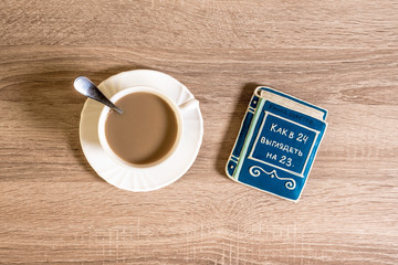 cup of morning coffee latte on a table with cookies in the form of a small book