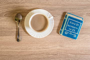 cup of morning coffee latte on a table with cookies in the form of a small book