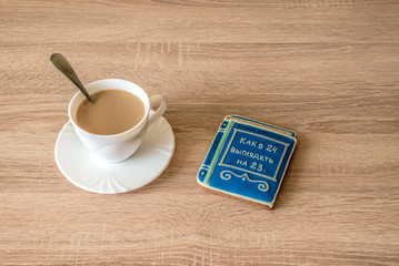cup of morning coffee latte on a table with cookies in the form of a small book