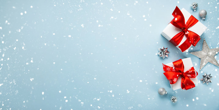 Merry Christmas and Happy Holidays greeting card, frame, banner. New Year. Noel. Christmas white and red ornaments and gifts on blue background top view. Winter xmas holiday theme. Flat lay.	