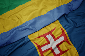 waving colorful flag of madeira and national flag of gabon.