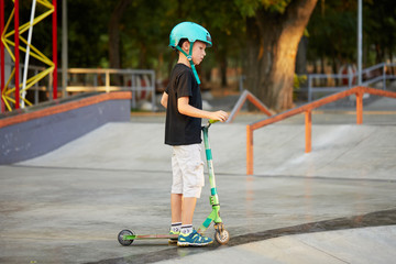 A boy on a scooter and in protective helmet do incredible stunts in skate park. Extreme jump. The concept of a healthy lifestyle and sports leisure © oes