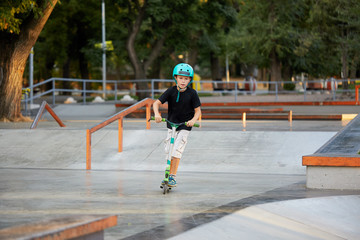 A boy on a scooter and in protective helmet do incredible stunts in skate park. Extreme jump. The...