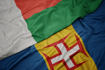 waving colorful flag of madeira and national flag of madagascar.