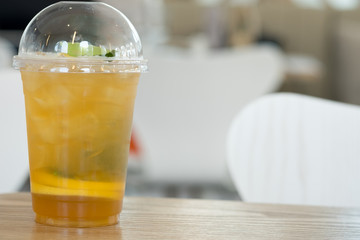 Plastic glass of tea lemonade on wooden table
