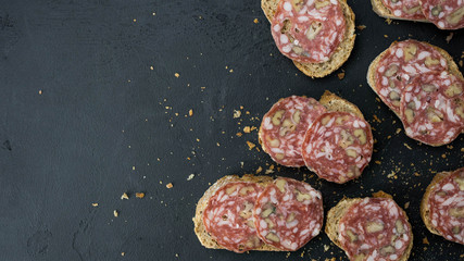 Kanapki z salami. Pyszne chrupiące śniadanie. Ciemne tło, widok z góry.