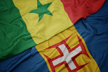 waving colorful flag of madeira and national flag of senegal.
