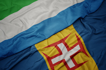 waving colorful flag of madeira and national flag of sierra leone.