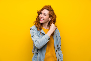 Redhead woman over isolated yellow background celebrating a victory