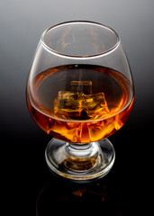 Tumbler glass with whiskey against a black background