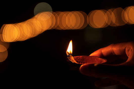 Closeup Image Of Person Holding Diwali Diya Background. Diwali or deepawali photo with woman or female holding oil lamp, diya during festival of light with space for text isolated on black background.