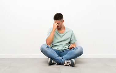 Young handsome man sitting on the floor laughing