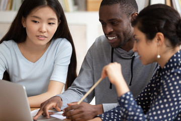 Multi-ethnic students sitting in classroom using computer educational apps